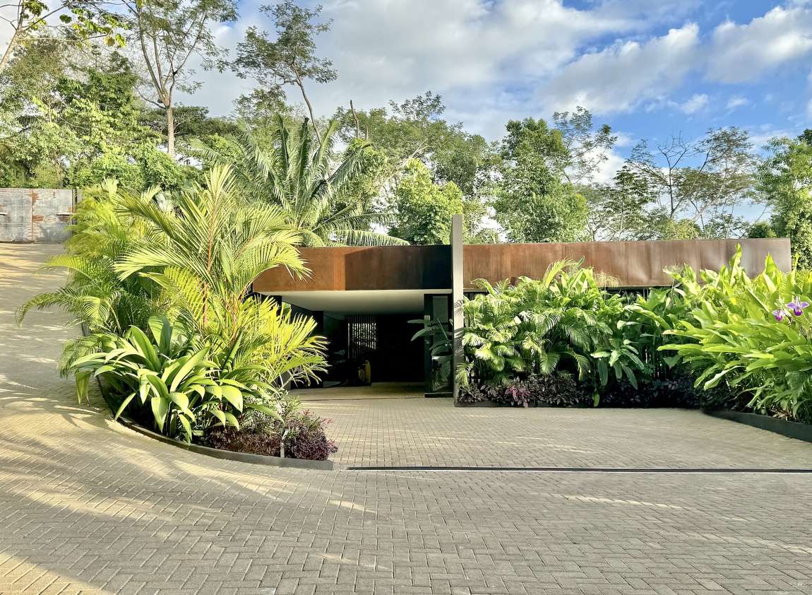 The arrival driveway, running along the weathered steel facade