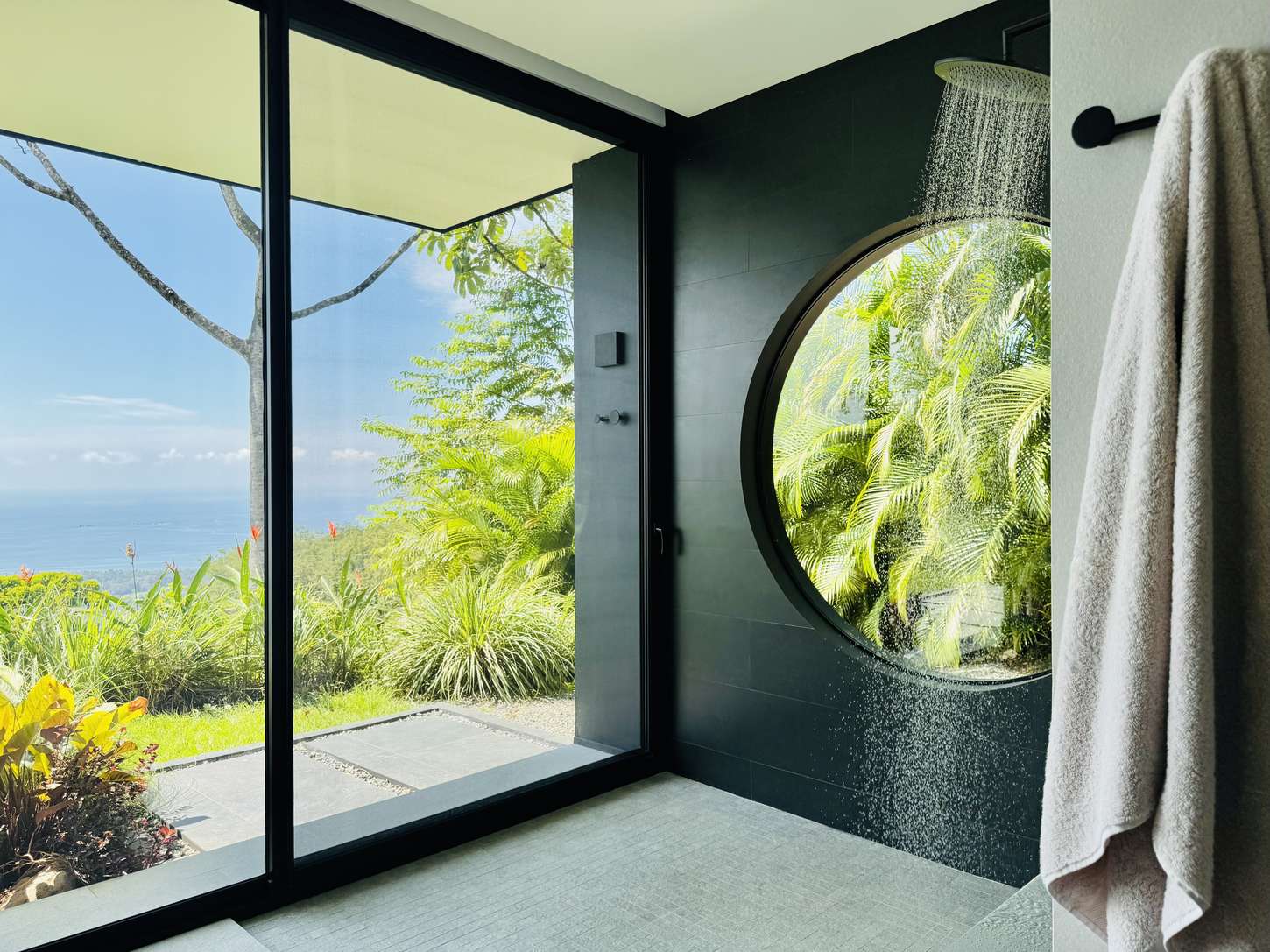 A shower glazed to the jungle, with a circular window alongside