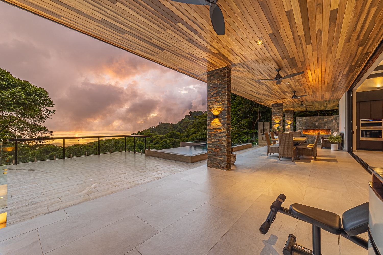 Casa Koules &mdash; the covered terrace at sunset, with the pool, the fire and the ocean beyond