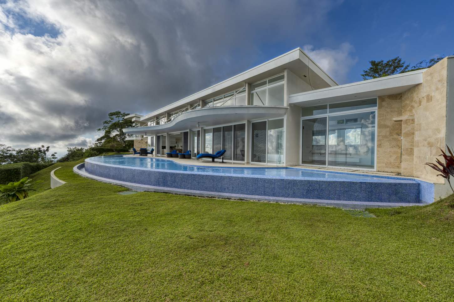 The house and pool across the lawn, with the jungle falling away behind