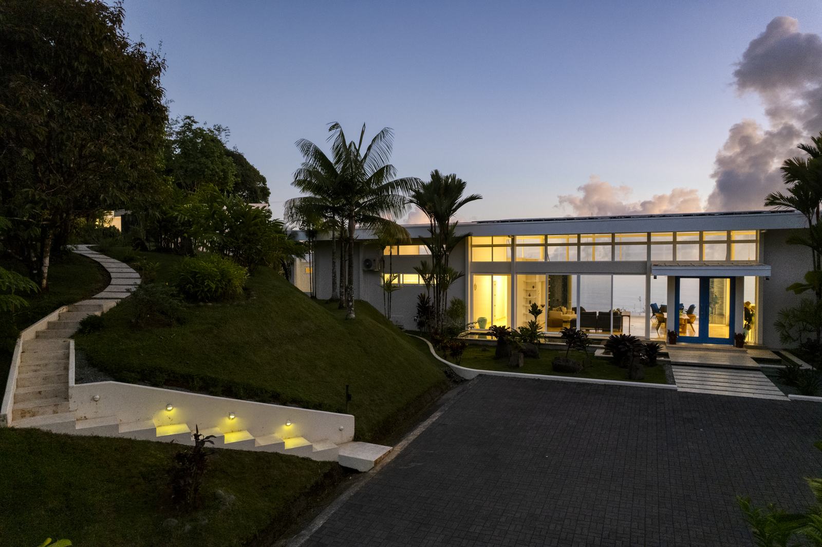 The house lit at dusk, seen from the garden path