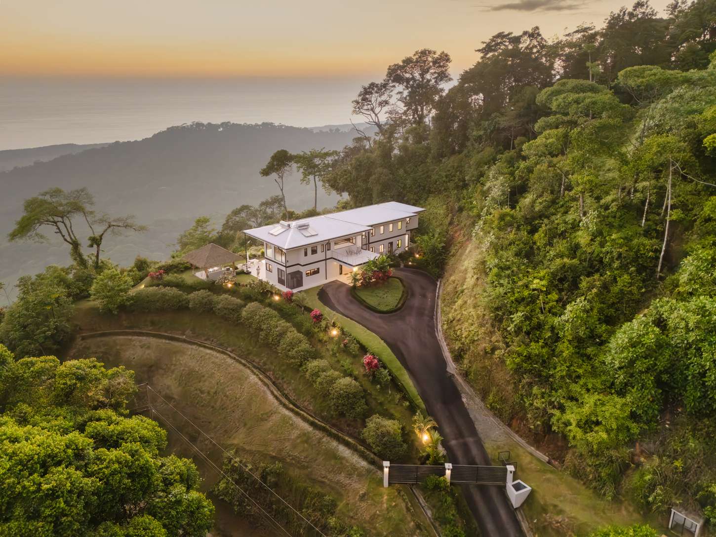 Casa Montaña — the house at dusk, its private drive climbing the ridge above Dominical