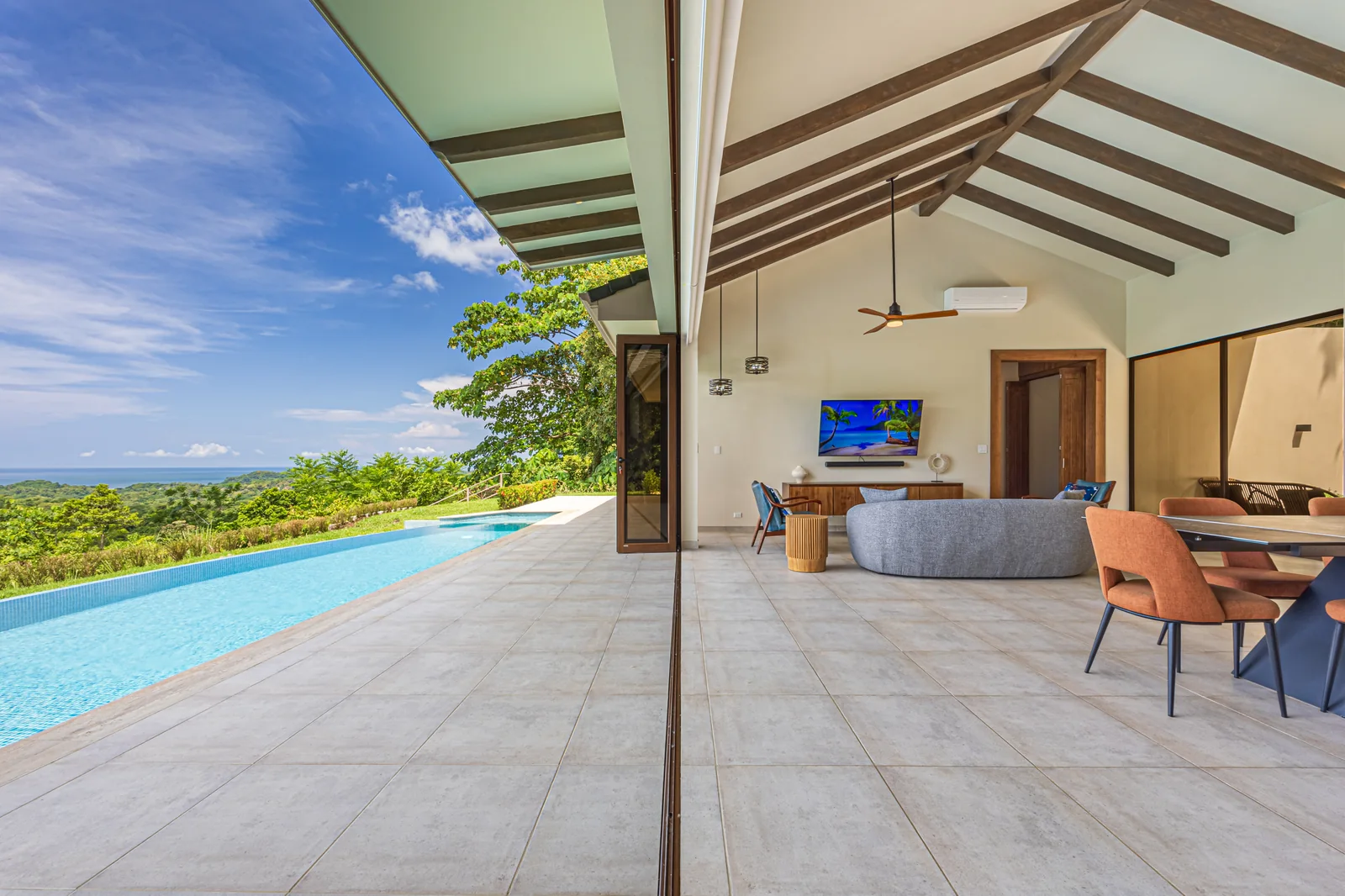 Casa Tranquilidad &mdash; the living room, its glass wall opened to the pool