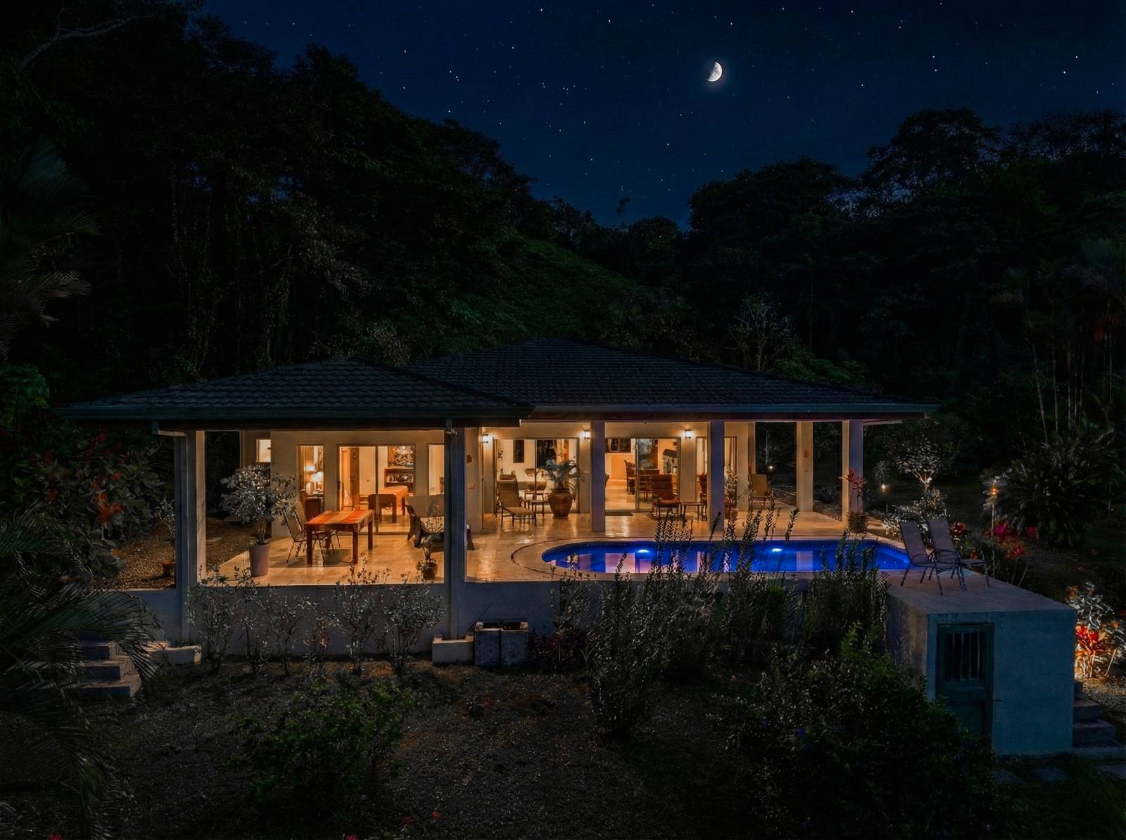 The house lit at night above the valley